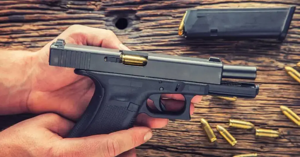 Hand holding a semi-automatic handgun with a visible bullet in the chamber, surrounded by scattered bullet casings and a magazine on a wooden surface, illustrating firearm-related legal issues in Florida.