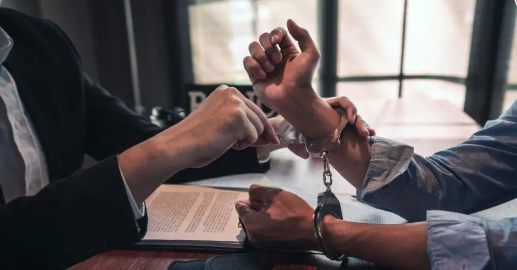 Lawyer assisting client with handcuffs in a legal consultation setting, focusing on resisting arrest with violence charges.