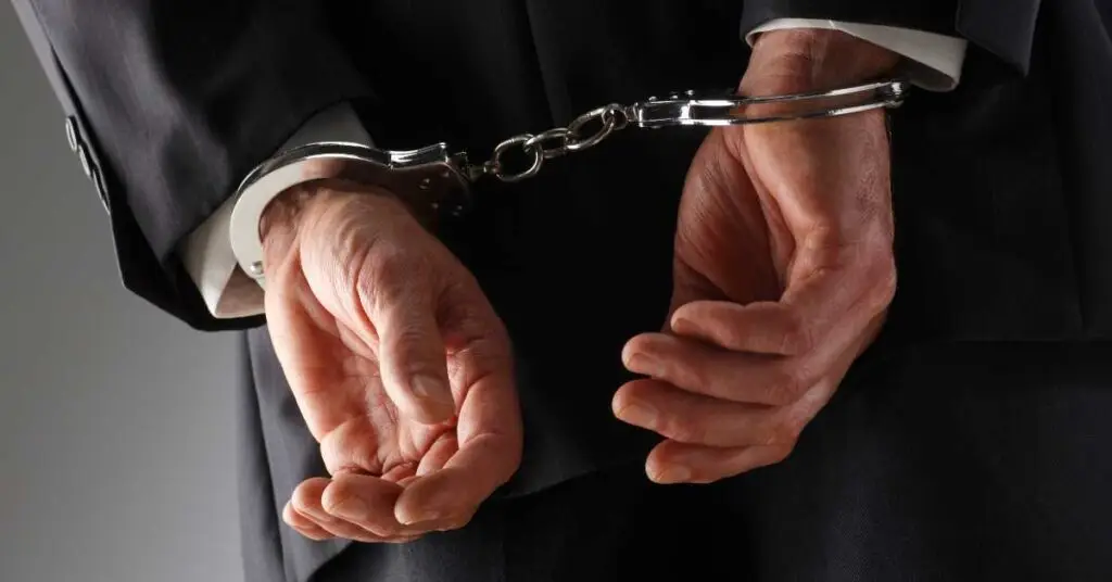 Hands in handcuffs wearing a suit, symbolizing legal issues and criminal charges for tourists in Fort Lauderdale.