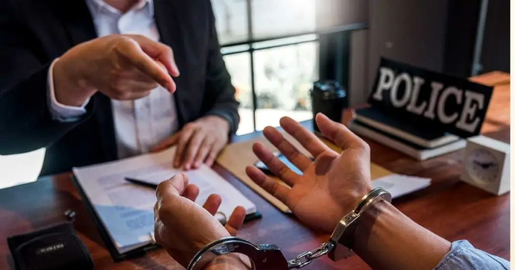 Criminal defense lawyer consulting with a handcuffed client in an office setting, emphasizing the importance of legal representation in criminal cases.