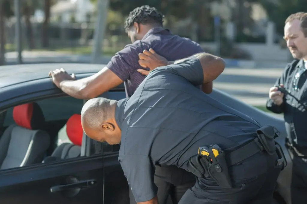 Police officer conducting a traffic stop, apprehending a driver near a vehicle, highlighting the implications of criminal traffic charges in Florida.
