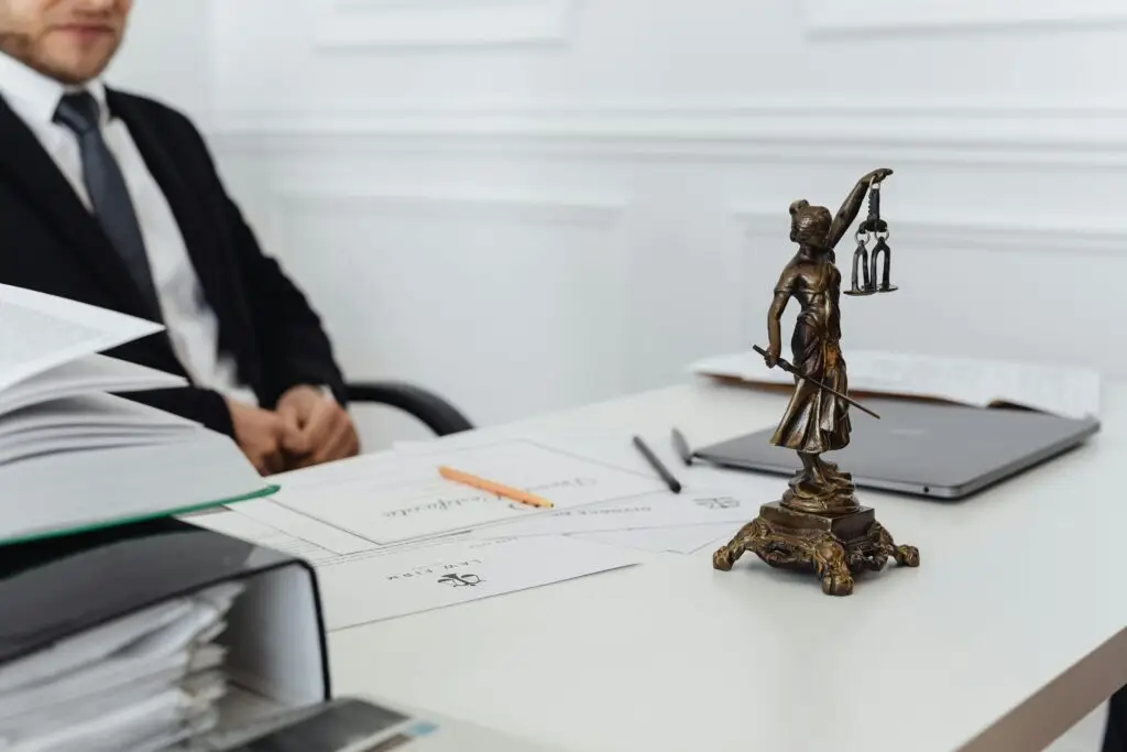 Close-up of a legal desk with Lady Justice statue and a defense lawyer in the background, representing battery defense in Fort Lauderdale.