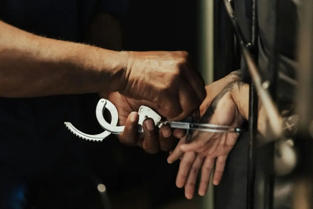 Close-up of an officer placing handcuffs on a young person, representing the need for a Fort Lauderdale juvenile defense attorney.