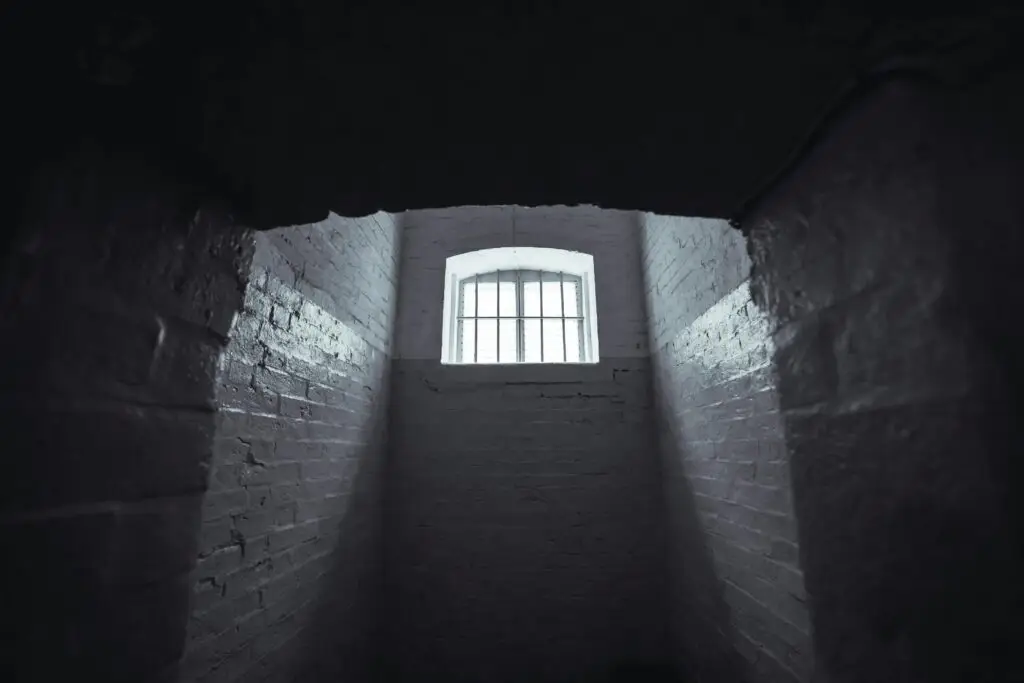 View of a barred window inside a dark detention cell, symbolizing the urgency of hiring a juvenile crime lawyer in Florida.